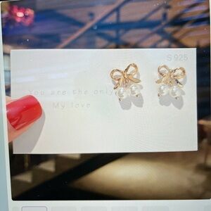 Fashion pierced earrings, gold tone bows with imitation pearl drops.